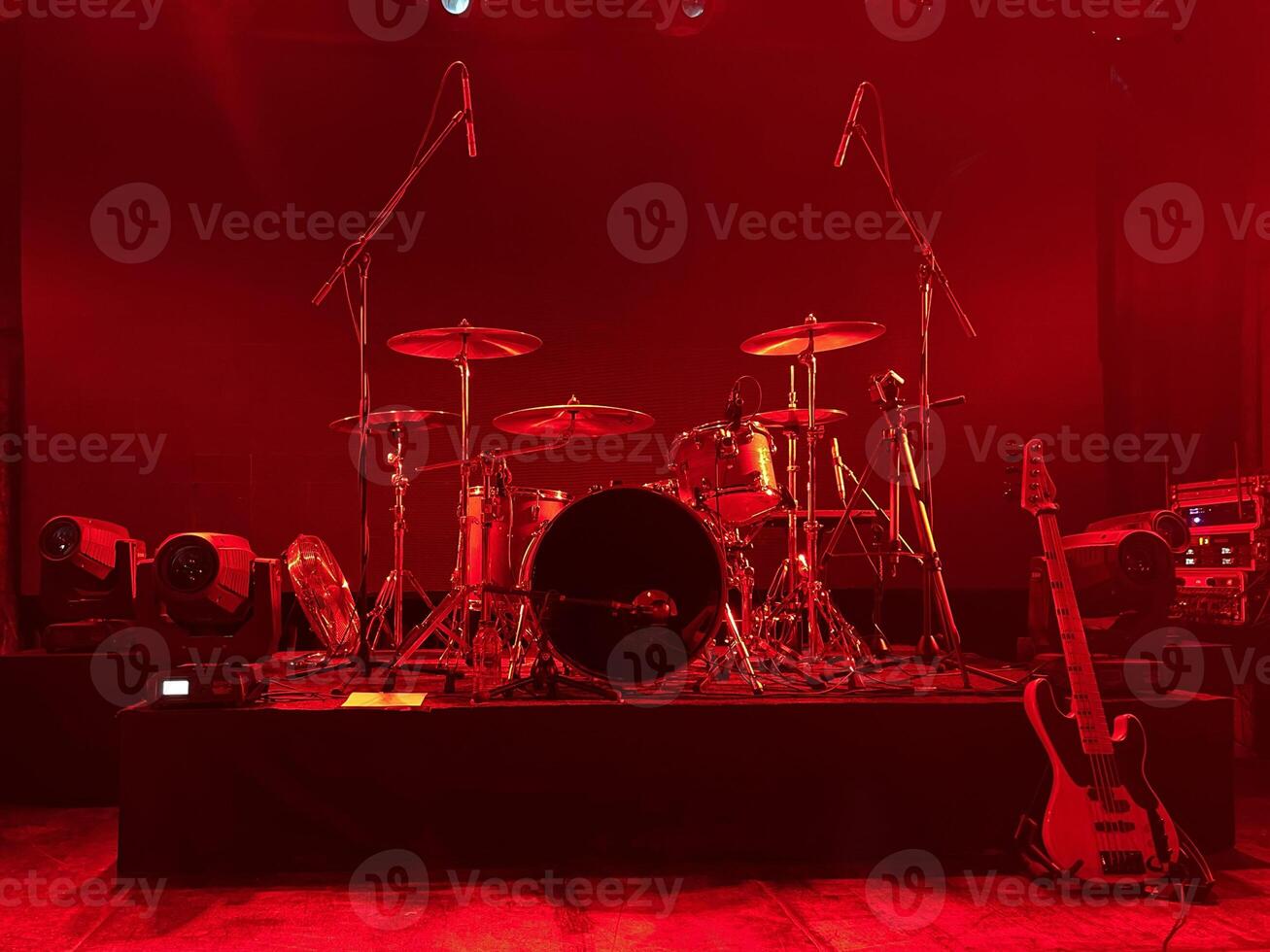 Exciting stage setup with drums and guitar under red lights, creating a thrilling atmosphere photo