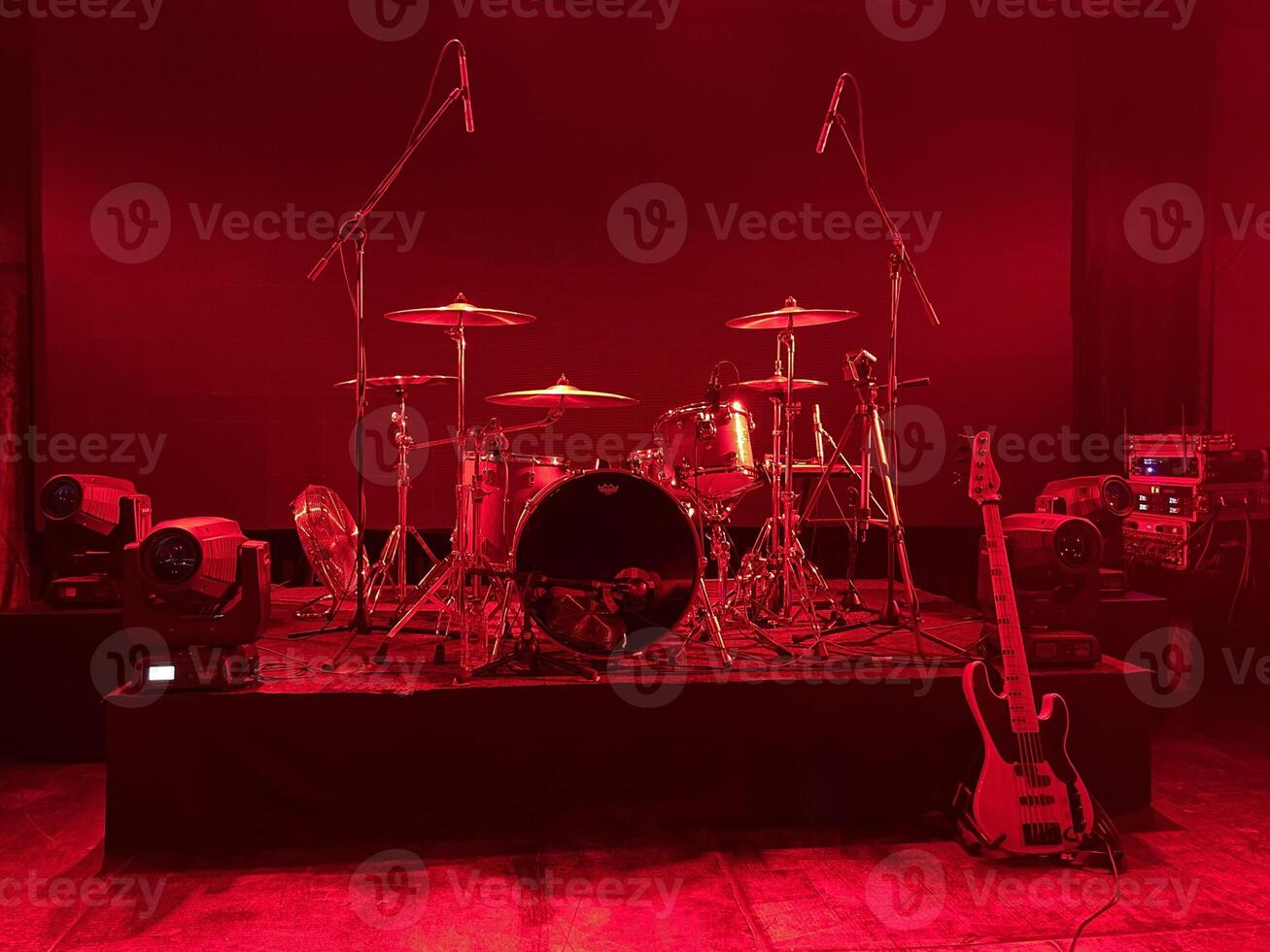 A beautifully illuminated stage setup featuring both drums and guitar for a live performance photo