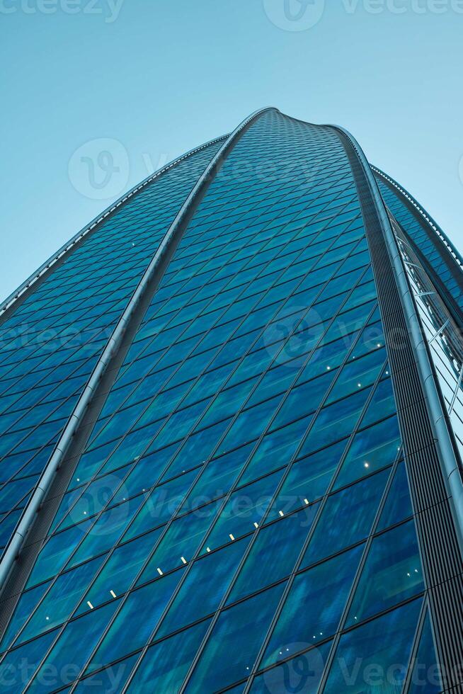 The Stunning Reflection of a Modern Skyscraper in the Vibrant Urban Environment Around It photo
