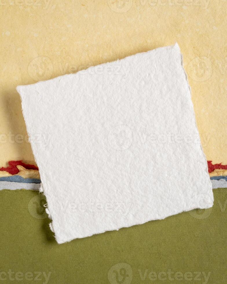 small sheet of blank white Khadi rag paper from India against abstract landscape in yellow and green pastel tones photo