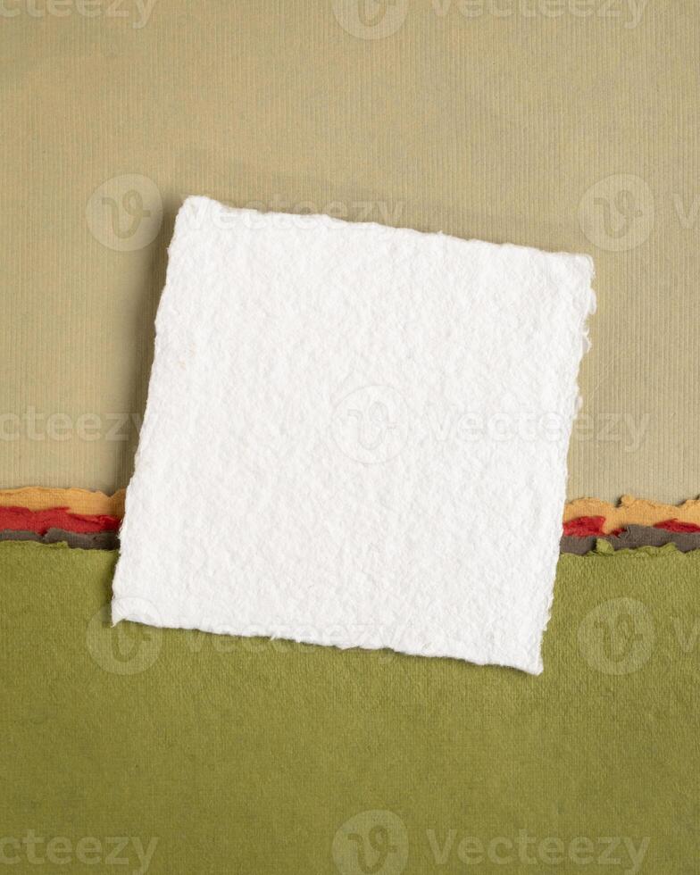 small sheet of blank white Khadi rag paper from India against abstract landscape in pink and green pastel tones photo