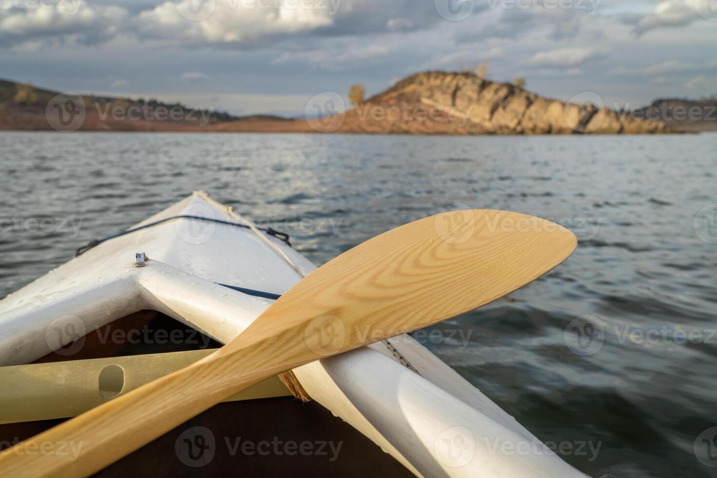 bow of a decked expedition canoe with wooden paddle on a mountain lake, paddler view - Horsetooth Reservoir in northern Colorado photo