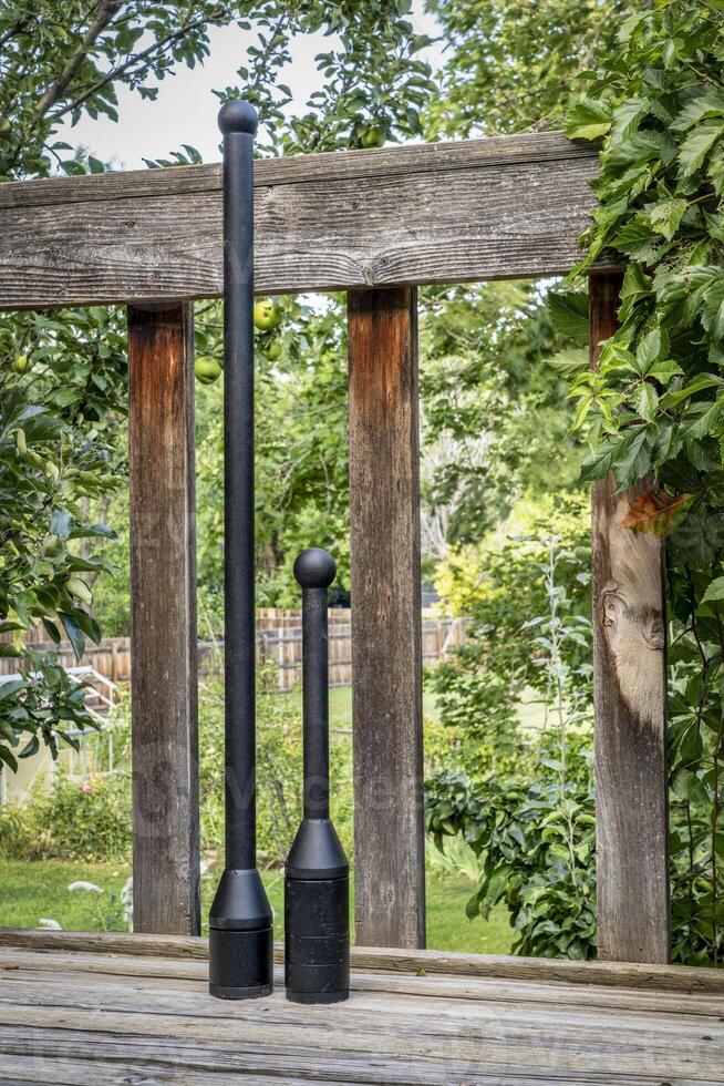 adjustable weight steel club and mace on a wooden backyard deck, functional fitness concept photo