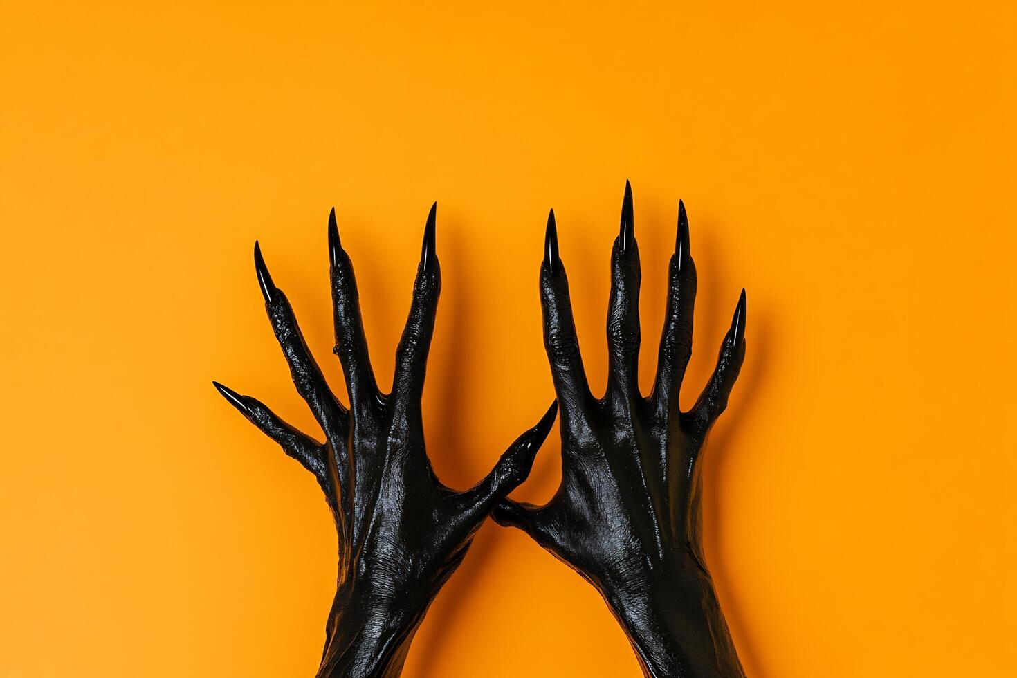 Hands of a black woman with long claws on an orange background photo