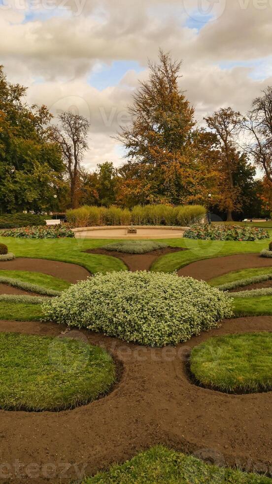 Beautiful green park with a fountain surrounded by trees in autumn in Royal garden Prague. Vertical mobile photo