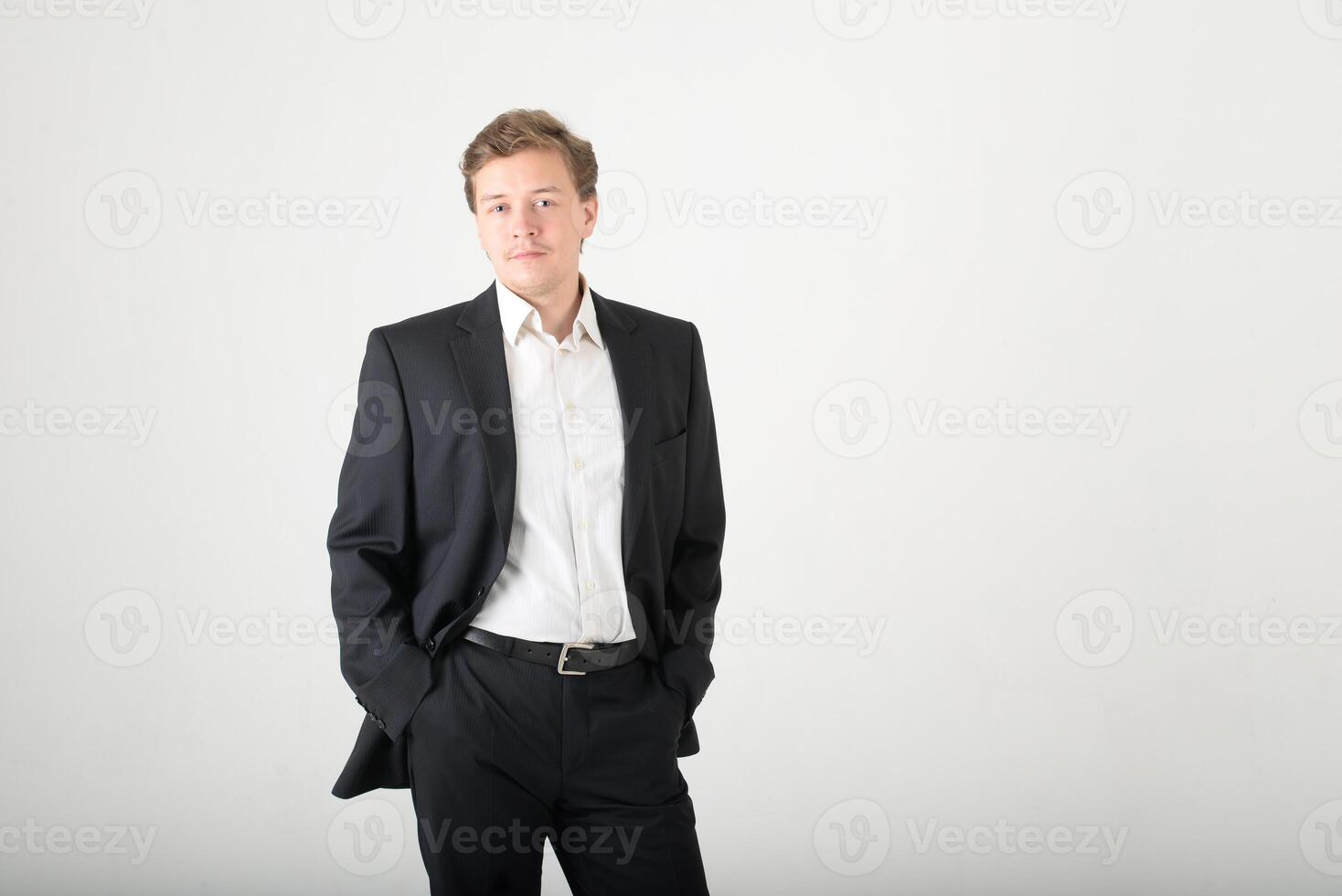 A young man wearing a black business suit with a white shirt on a white background with copy space. Business success concept photo