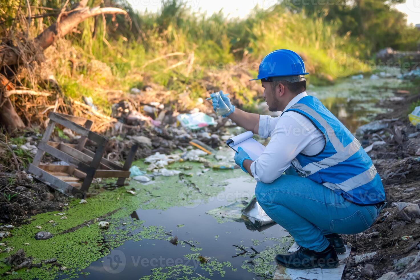 Water resource experts check the water quality in a community canal contaminated with garbage in the canal. photo
