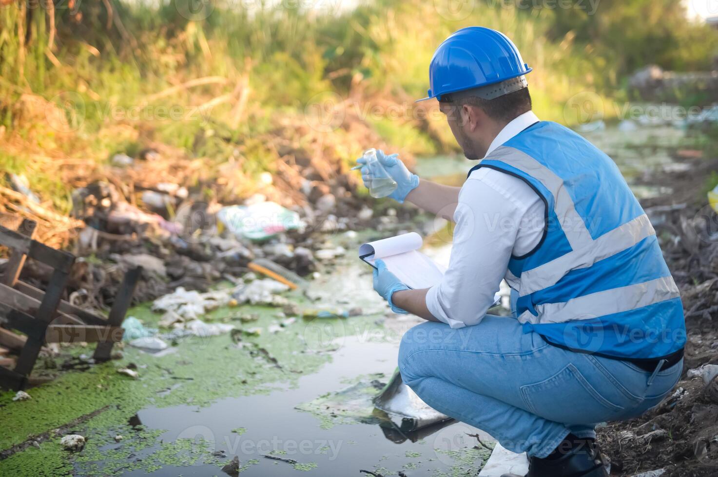 Water resource experts check the water quality in a community canal contaminated with garbage in the canal. photo