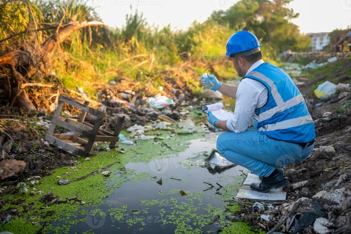 Water resource experts check the water quality in a community canal contaminated with garbage in the canal. photo