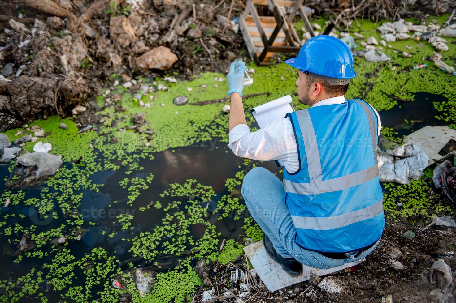 Water resource experts check the water quality in a community canal contaminated with garbage in the canal. photo