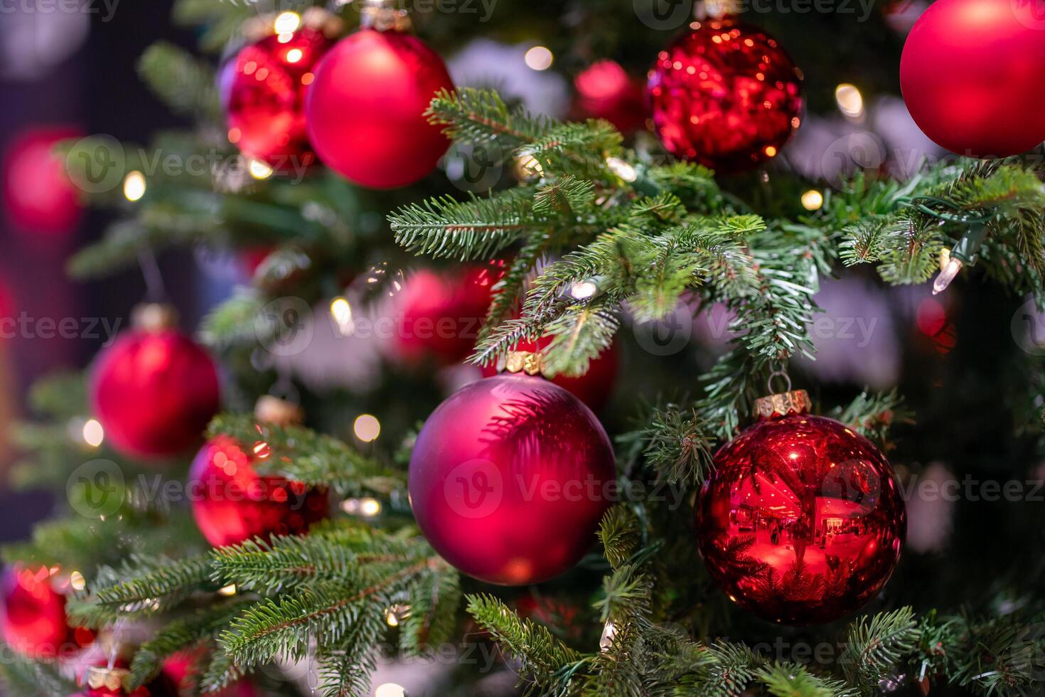 Green artificial fir branches decorated with red balls with garland lights photo