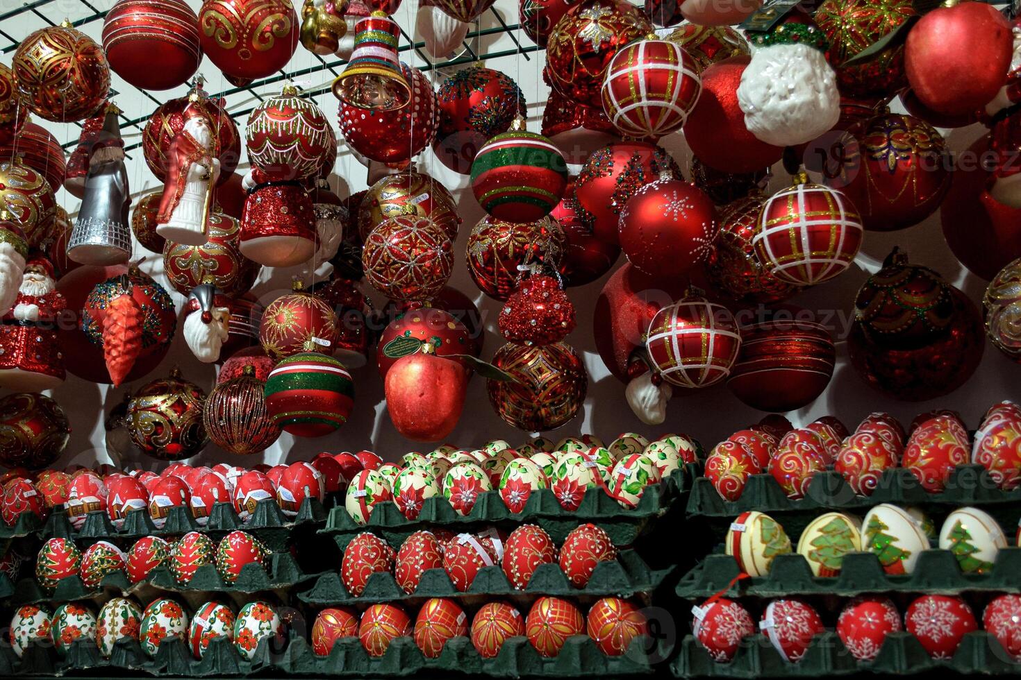 A variety of red Christmas tree toys hanging in a shop window photo