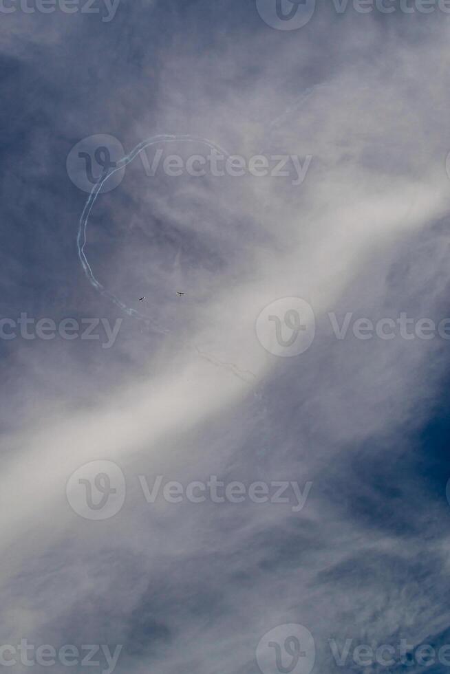 two planes draw a heart on the blue sky against the background of white clouds photo