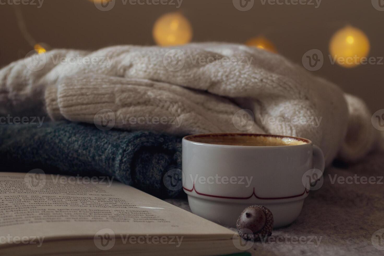 Warm knitted sweater, hot black coffee and a book for cozy evening reading photo