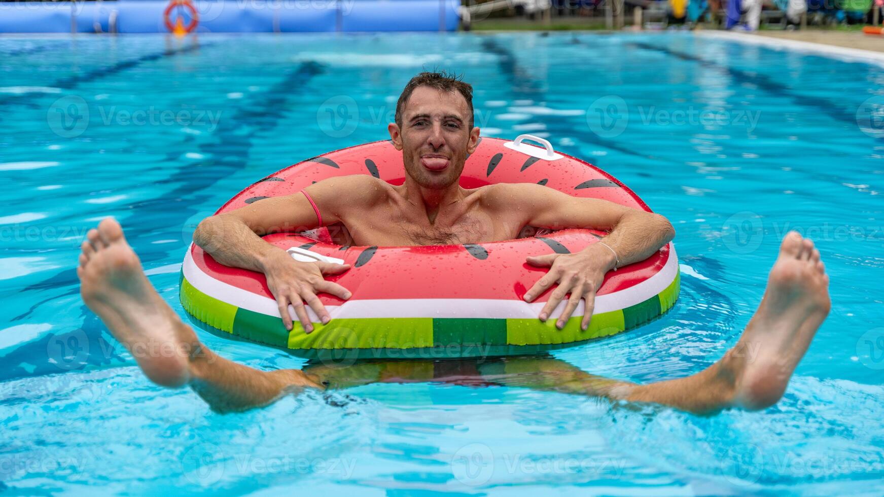portrait of young adult in swimsuit having fun in the water of a swimming pool inside a life ring photo