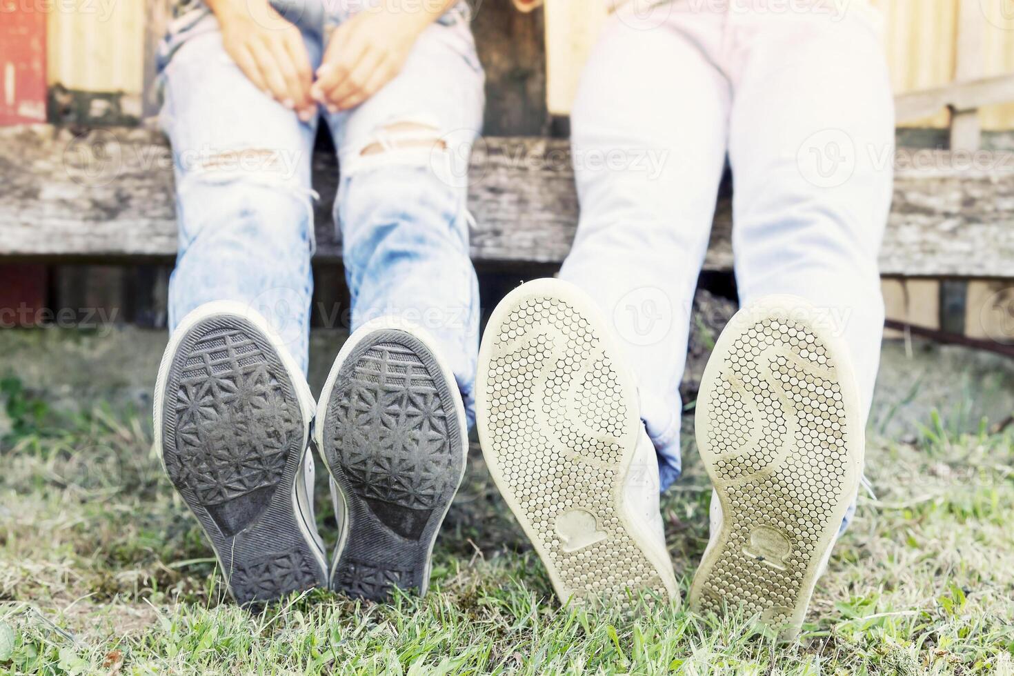 young couple sitting in the park with his feet foreground photo