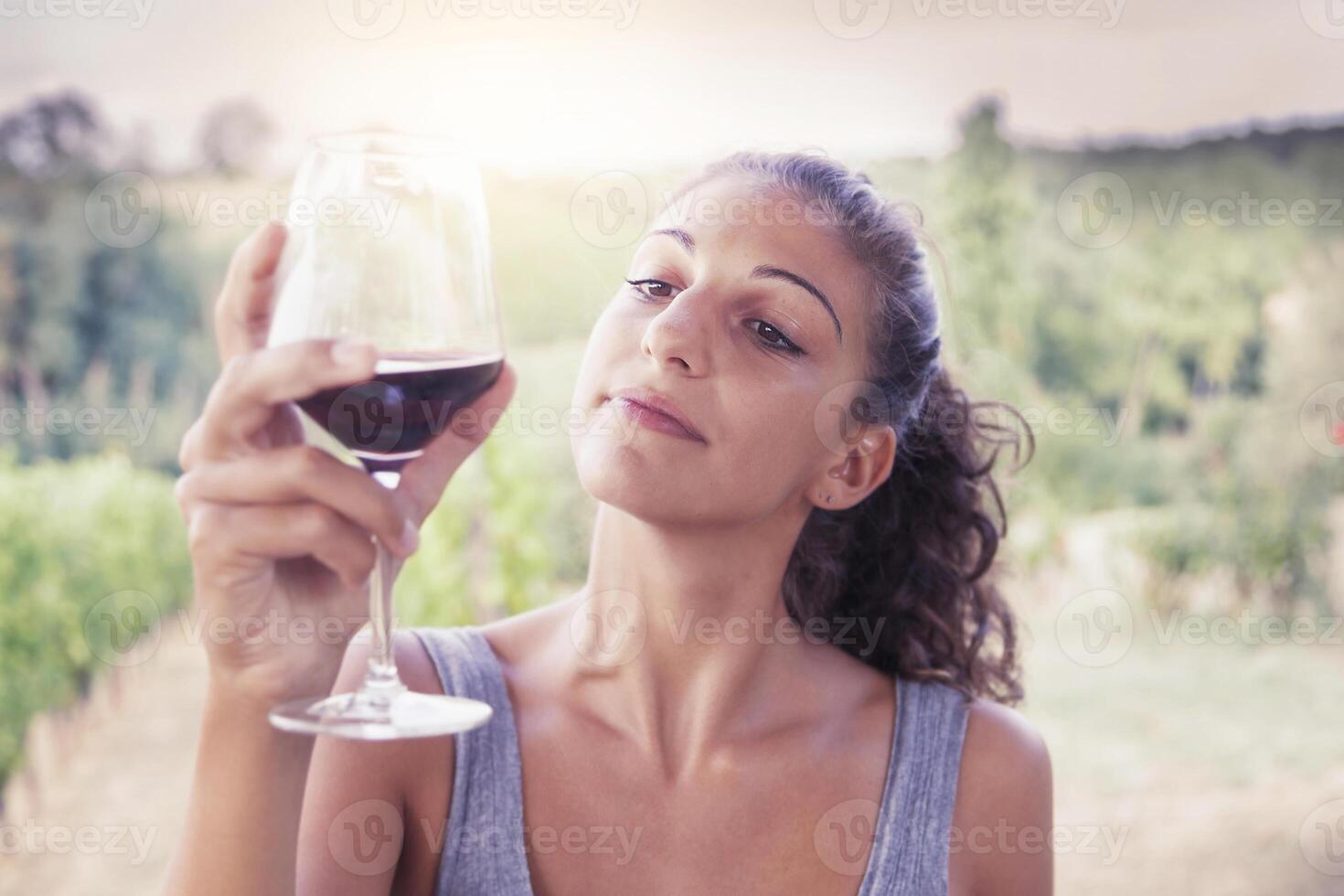 pretty girl looking glass of wine before drinking photo