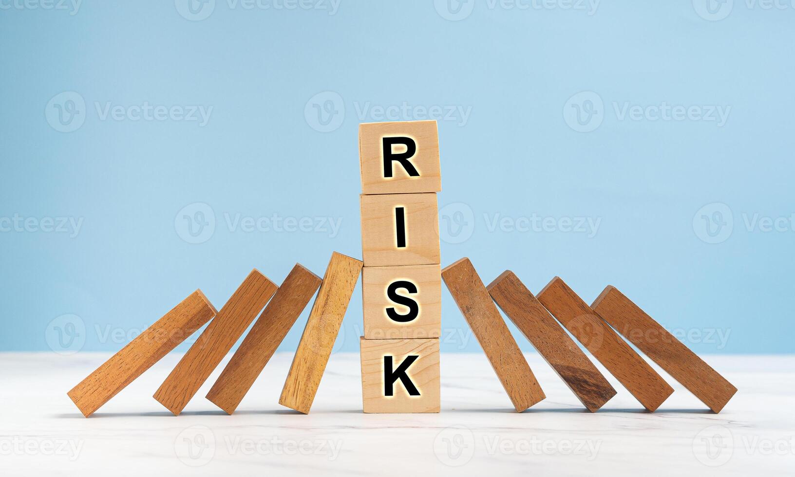 Risk management and strategy in business. Close-up of wooden blocks on a line of dominos over a marble floor with a blue background photo