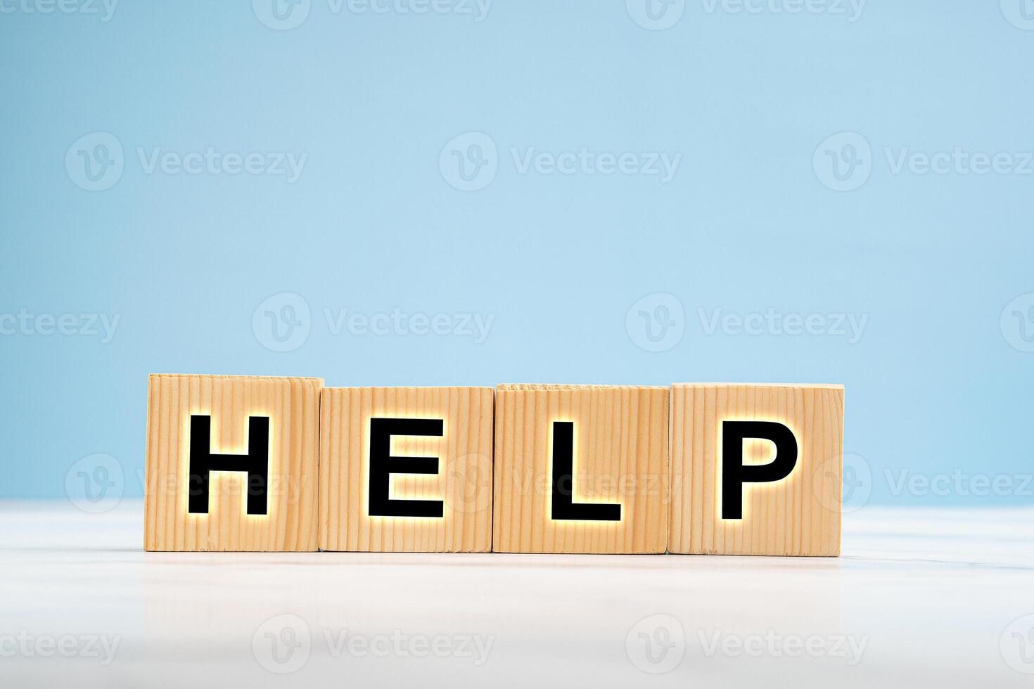 Wooden cubes with the letters HELP over a marble floor with a blue background photo