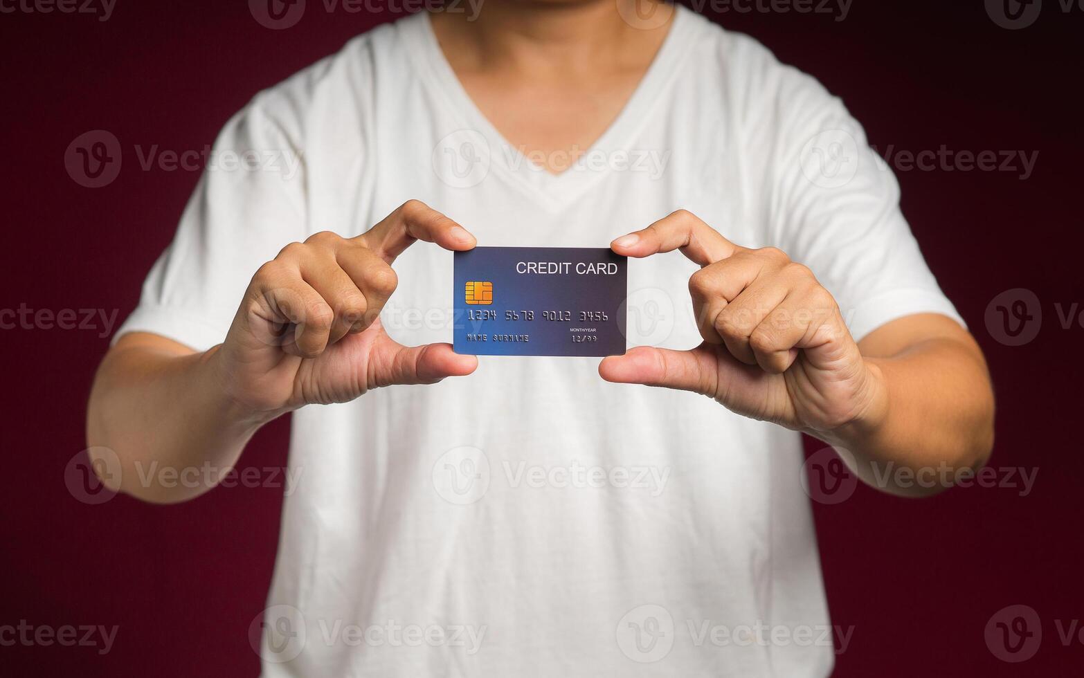 Close-up of hand holding a mockup credit card while standing on a red background photo