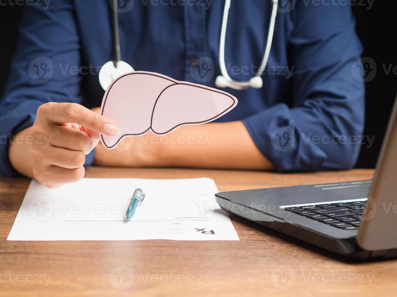 Close-up of hand doctor holding a liver shape made from pink paper while sitting in the hospital photo