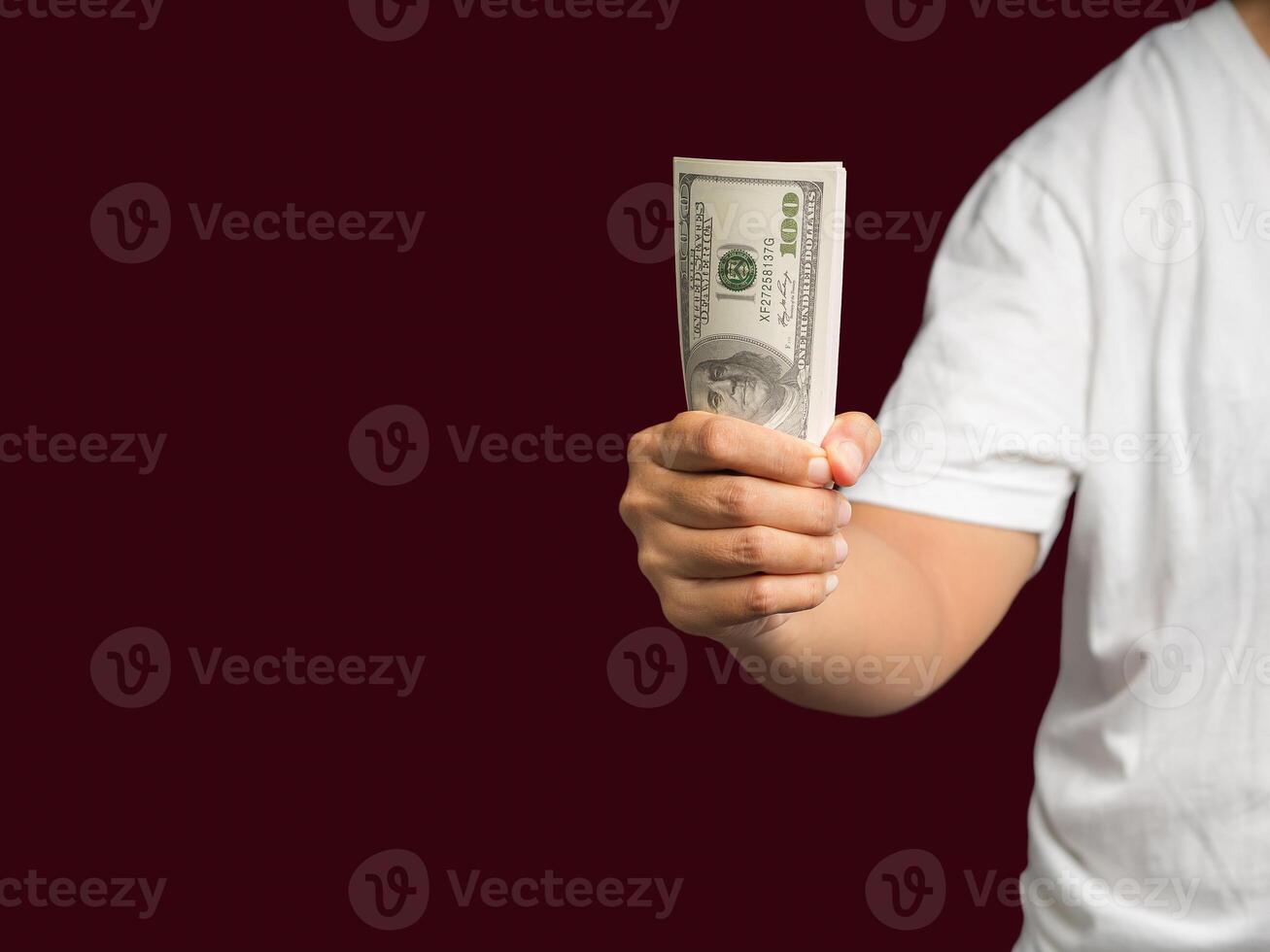 Man in a white casual holding US banknotes while standing on a red background photo