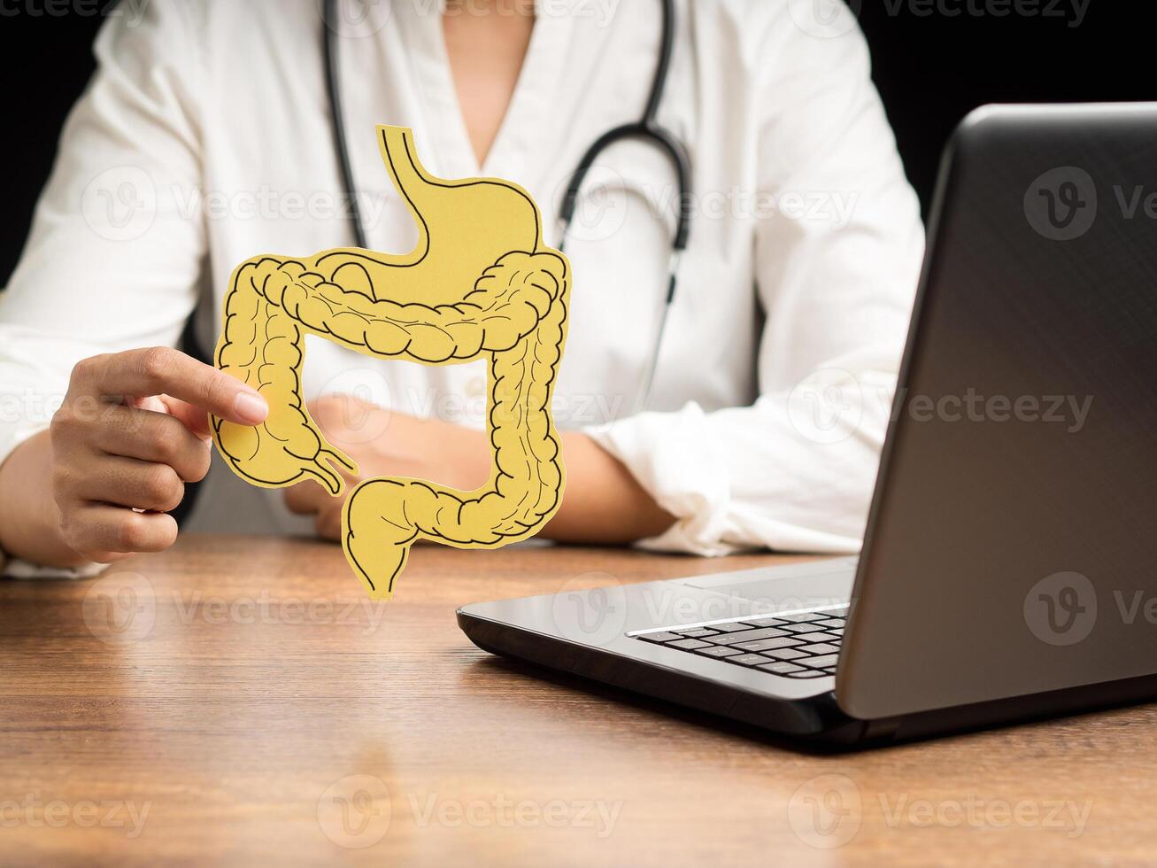 A doctor is holding a large intestine mockup while sitting in the hospital photo