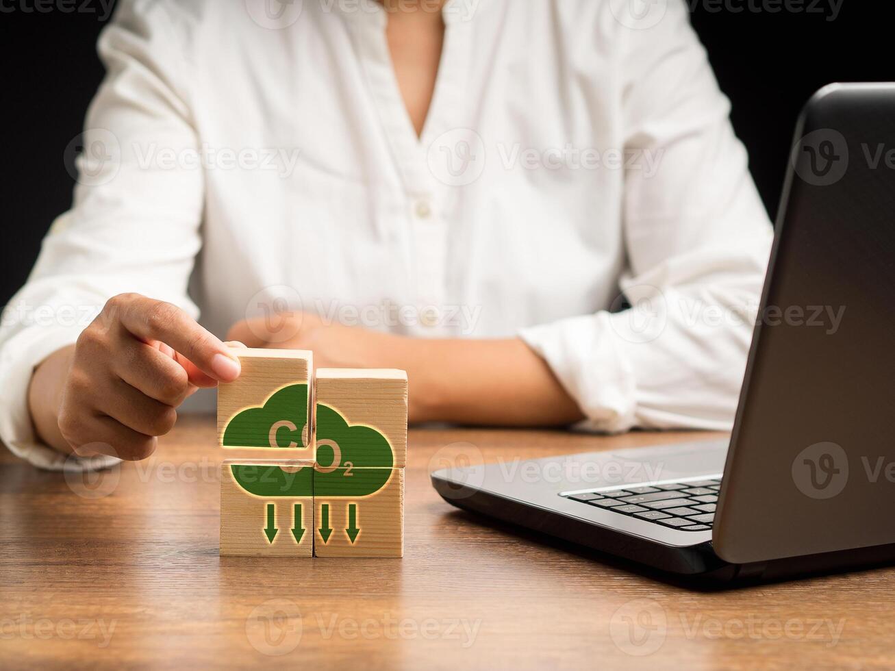 Net-zero greenhouse gas emissions target. Close-up of hand-holding of a wooden cube with CO2 green icons over a wooden table photo