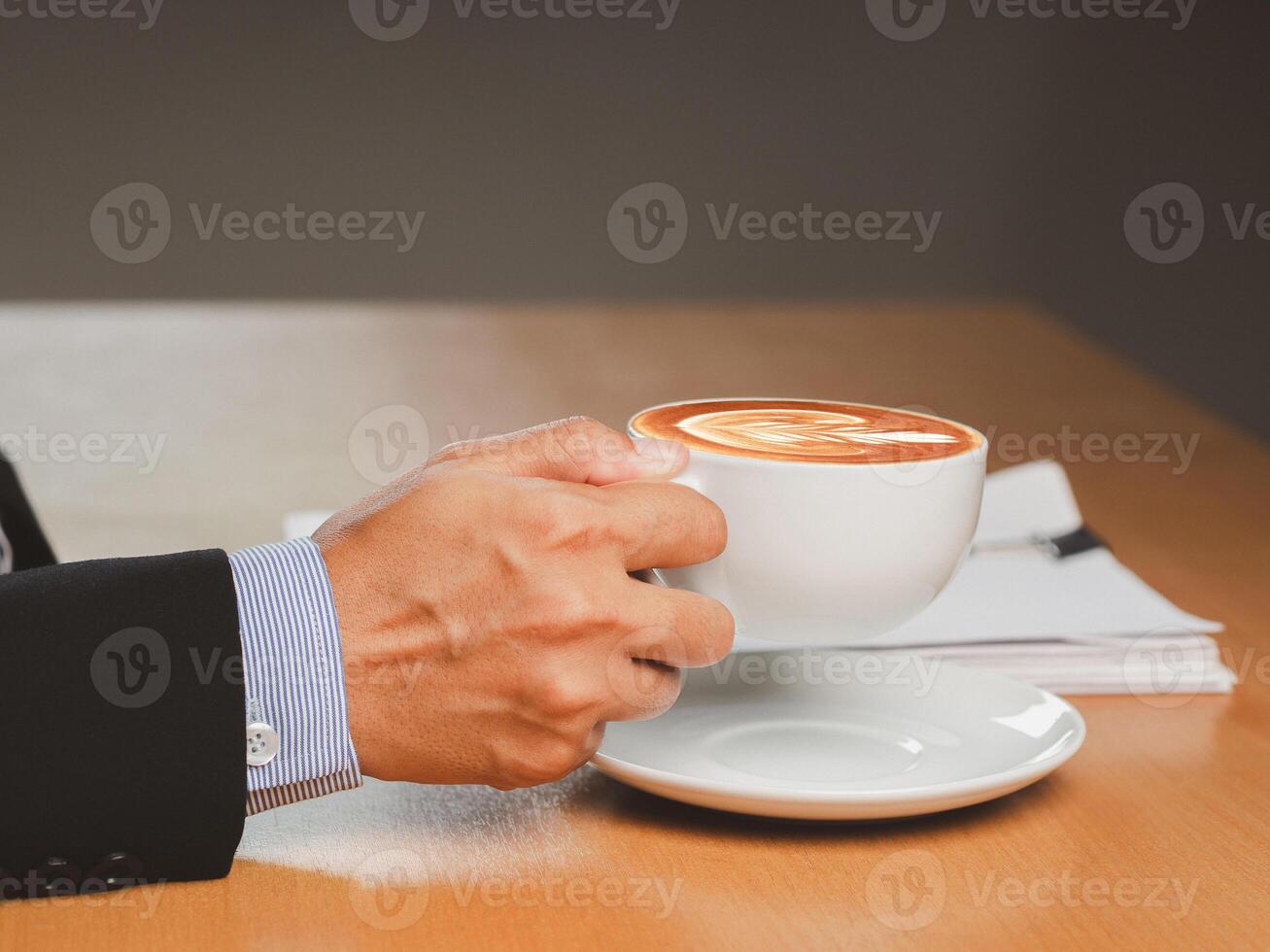 Businessman hand holding a cup of coffee sitting working at the office photo
