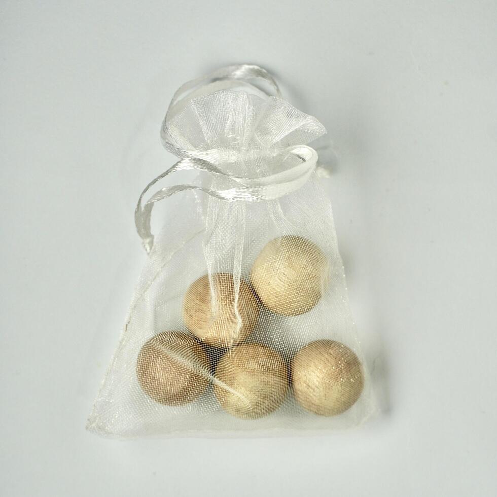 Anti smell odor and insect wooden balls for replacing camphor in white transparent pouch bag isolated on square white background from above angle view. photo