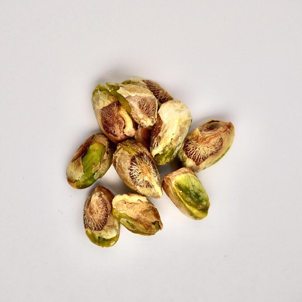 Pile of pistachio nuts without shells isolated on square white background from top view angle. photo
