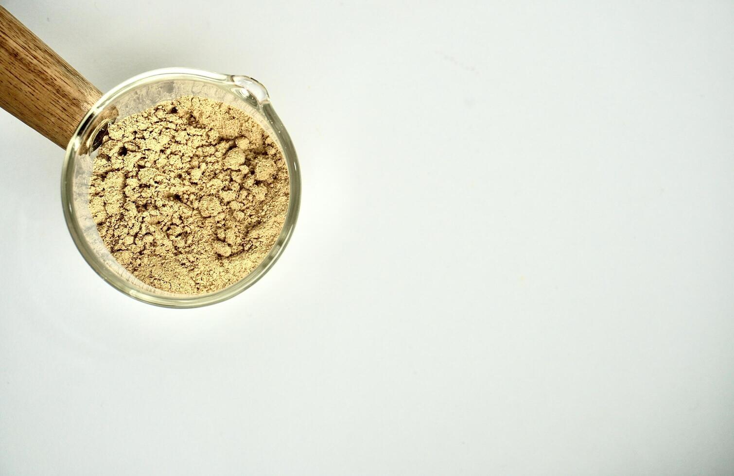 Green coffee powder food ingredients in small glassware cup pot isolated on horizontal copy spaced white background. photo