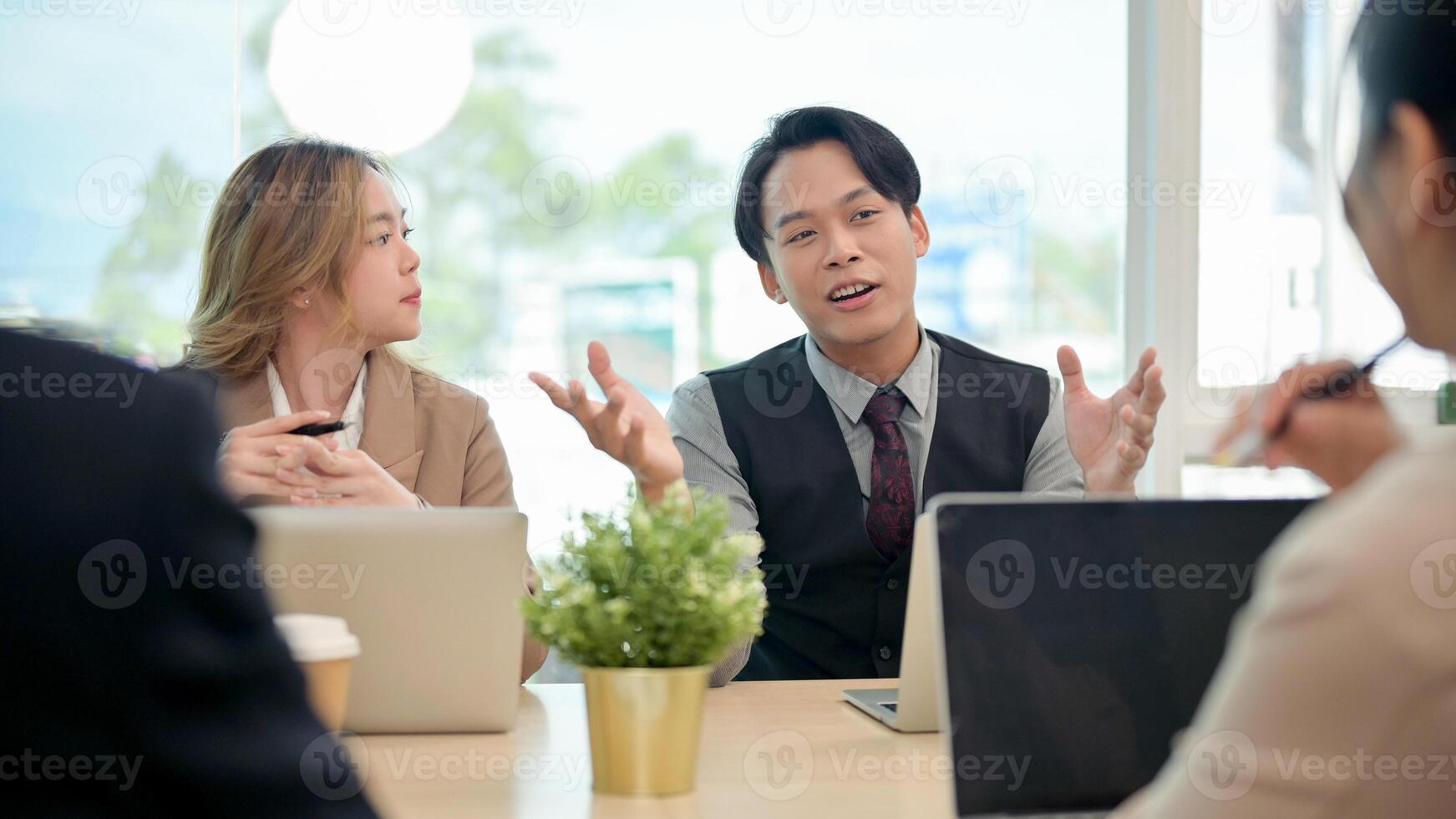 A smart Asian businessman confidently shares his ideas to his team during a business meeting. photo