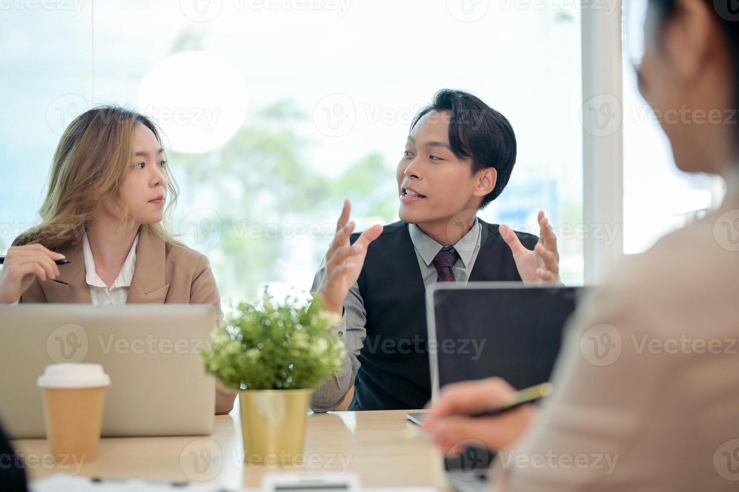 A smart Asian businessman confidently shares his ideas to his team during a business meeting. photo