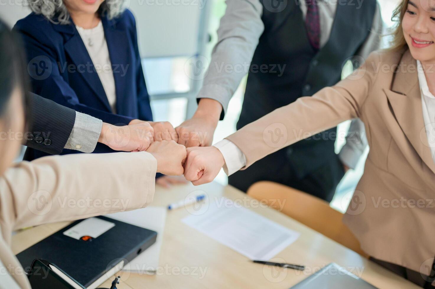 A close-up of diverse businesspeople fist bumping after a productive meeting in a modern office. photo