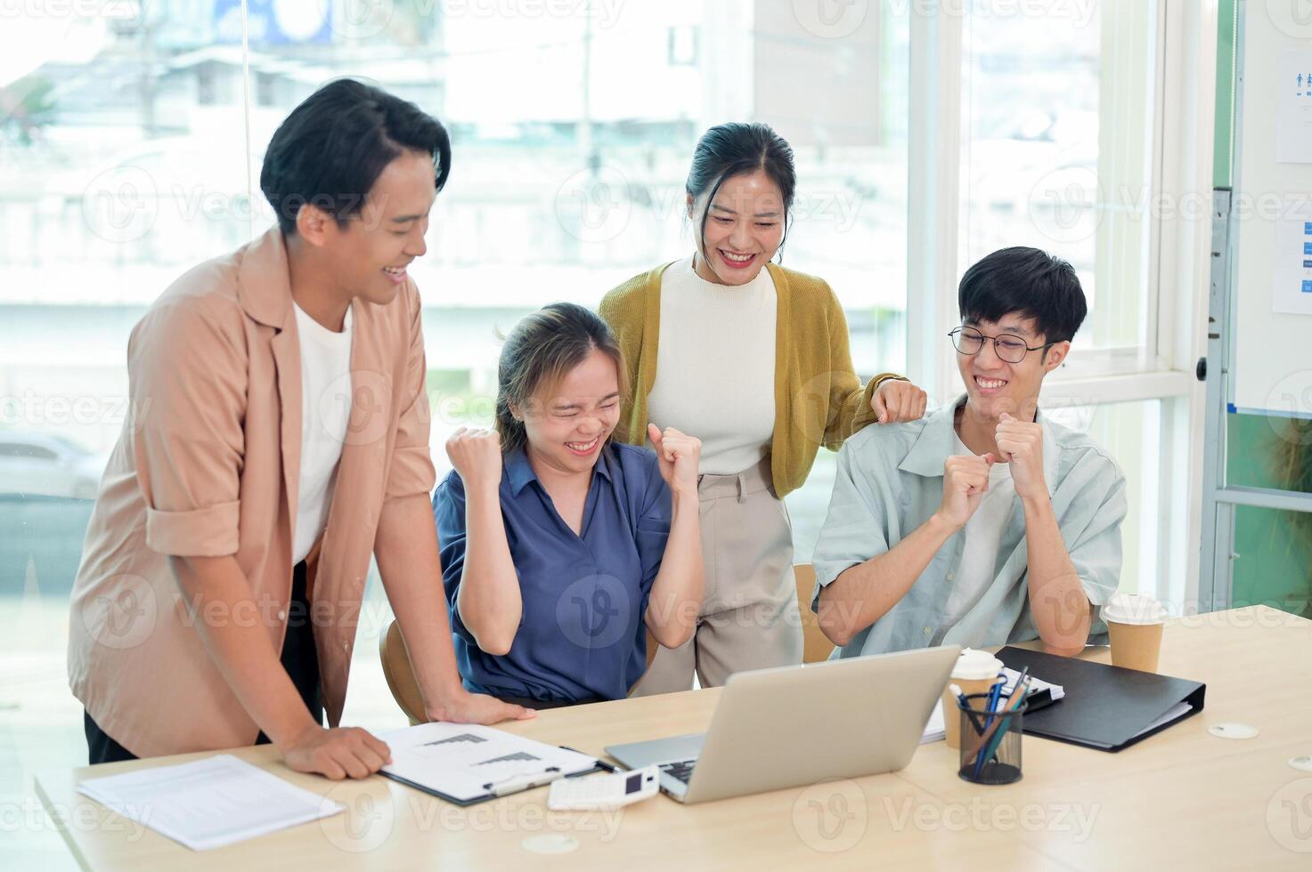 A cheerful young adult Asian business startup team celebrates their good news together. photo