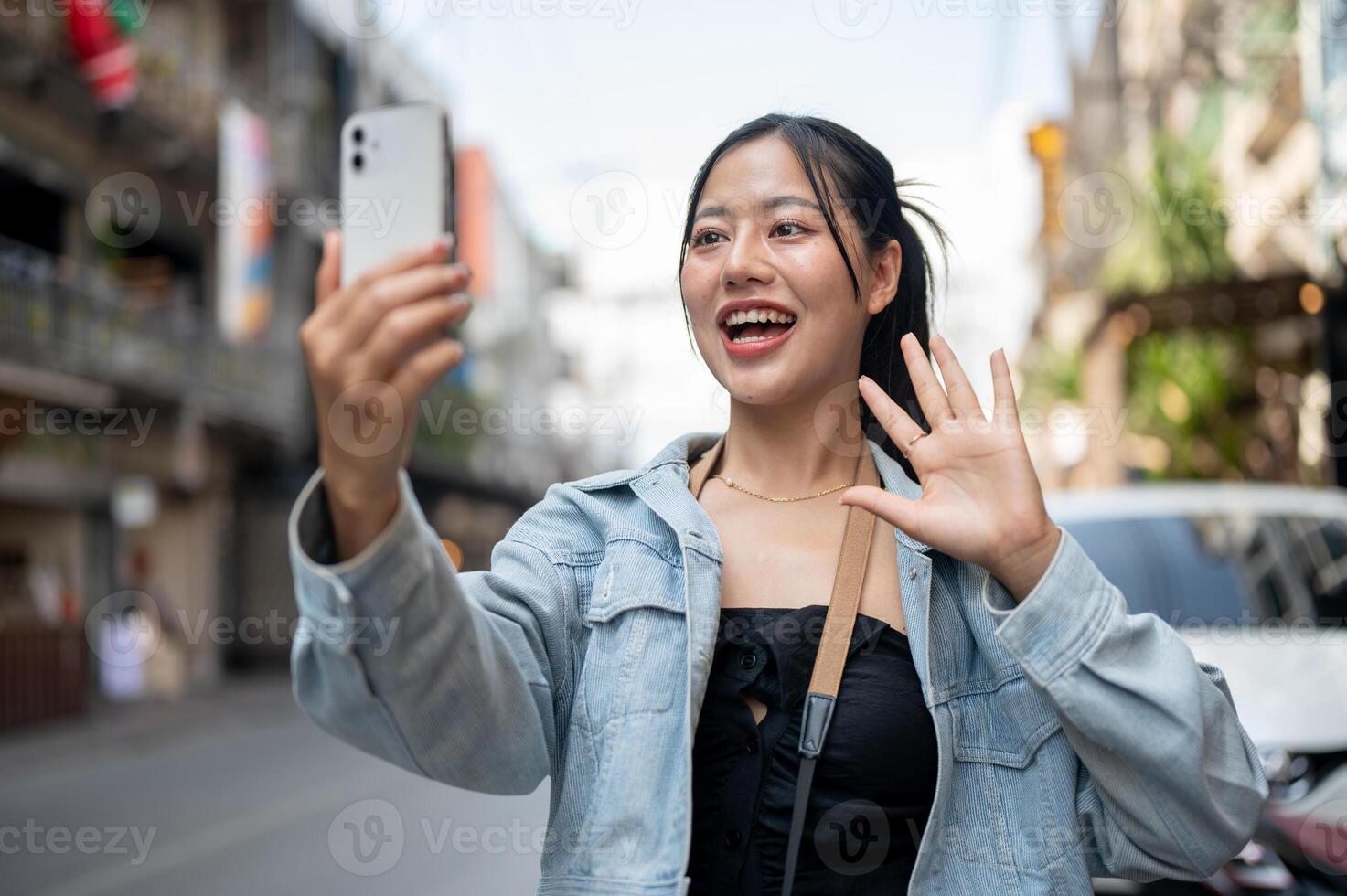 Cheerful Asian female tourist enjoying talking on a call or blogging while exploring the city. photo