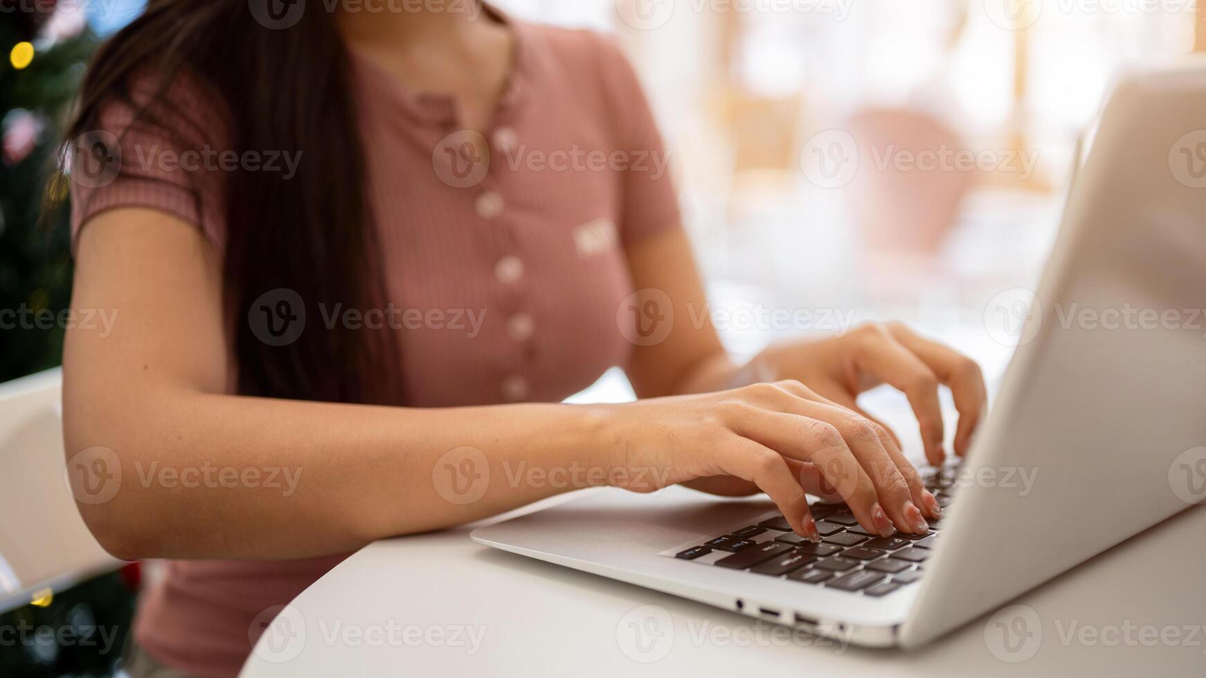 A woman working on her laptop computer, typing on the laptop keyboard, sitting in a cafe. photo