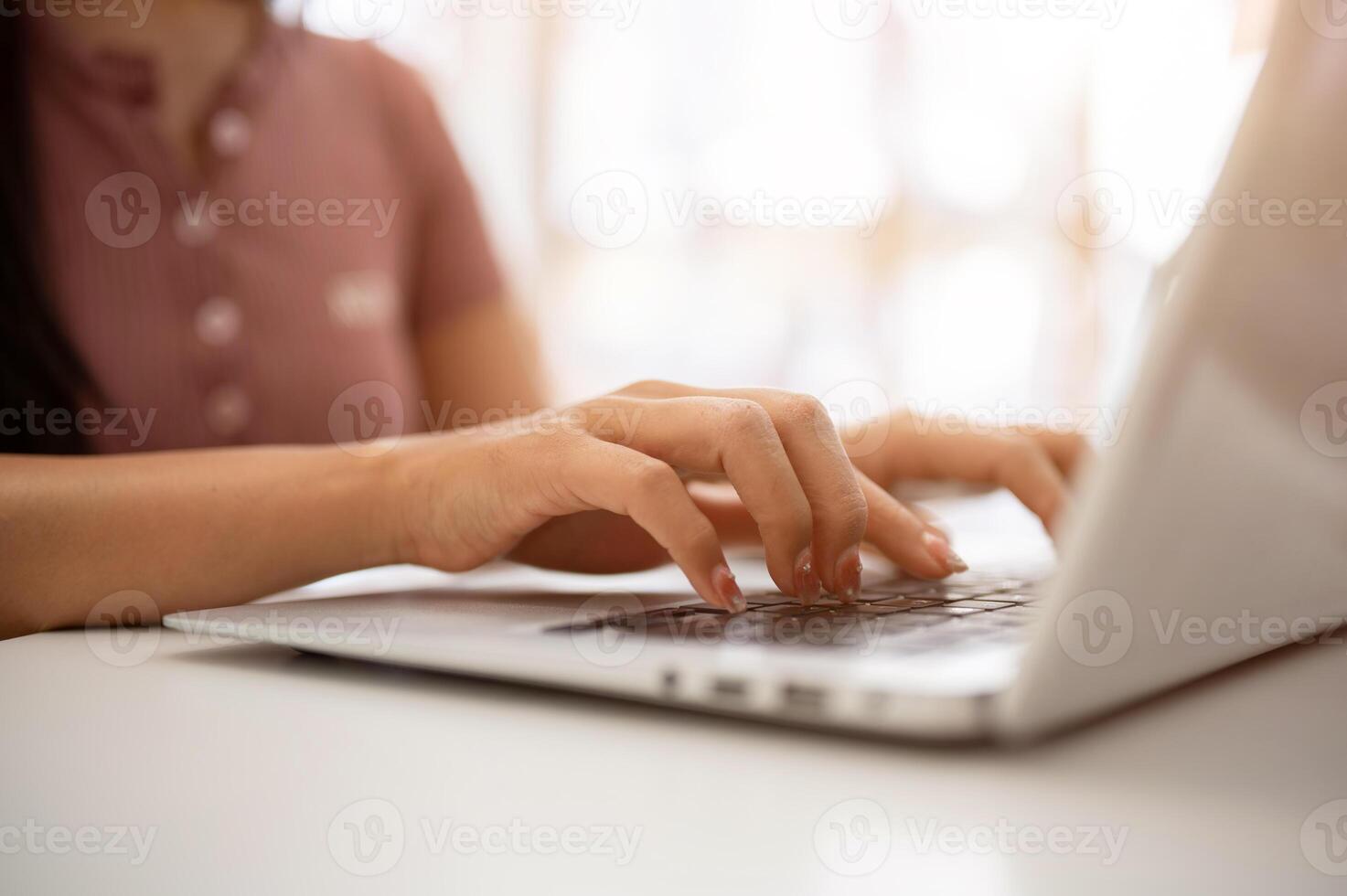 A woman working on her laptop computer, typing on the laptop keyboard, sitting in a cafe. photo