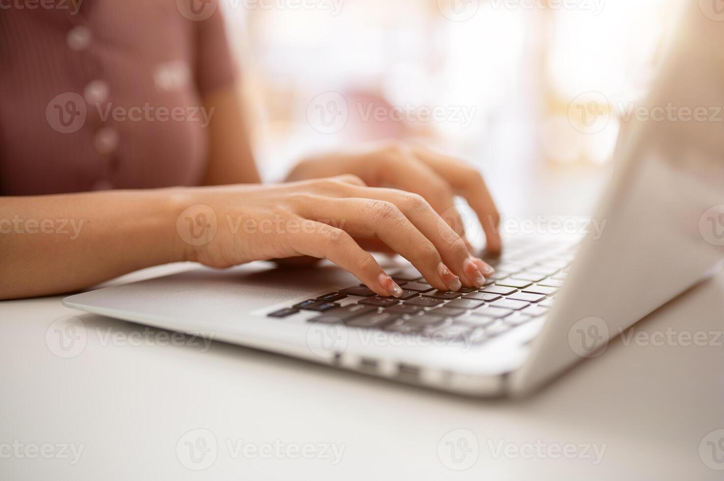 A woman working on her laptop computer, typing on the laptop keyboard, sitting in a cafe. photo