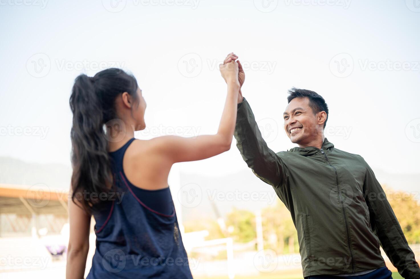 Cheerful friends give each other a high five to celebrate their success after running at a stadium. photo