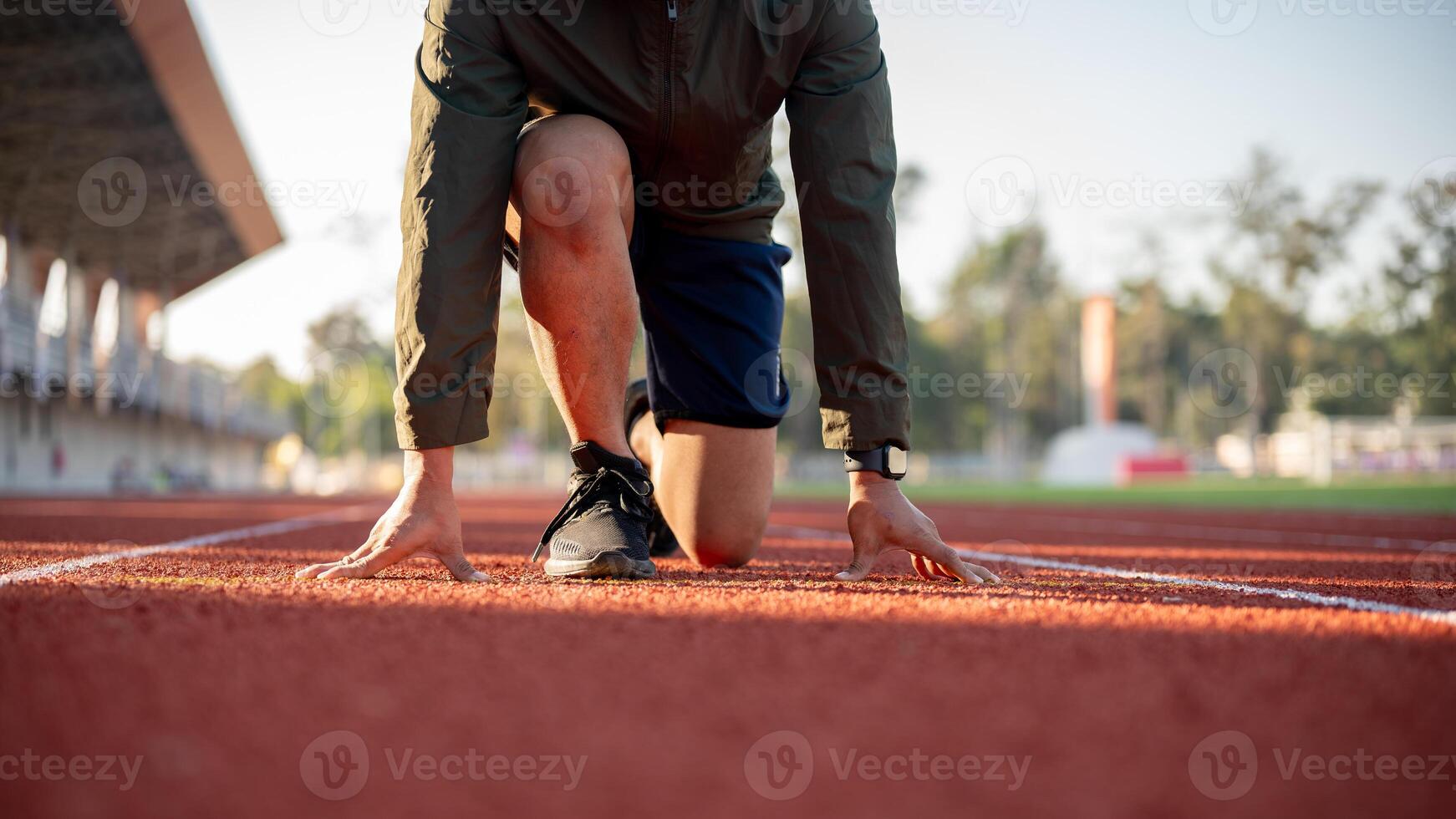 A cropped image of a strong man athletic runner in sportswear training in a stadium in the morning. photo