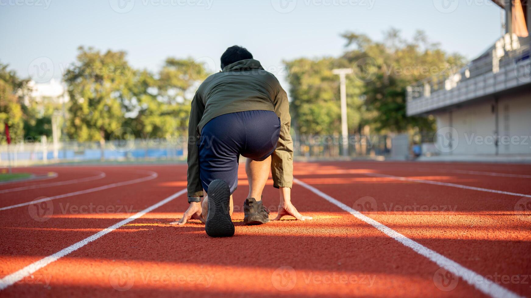 A cropped image of a strong man athletic runner in sportswear training in a stadium in the morning. photo