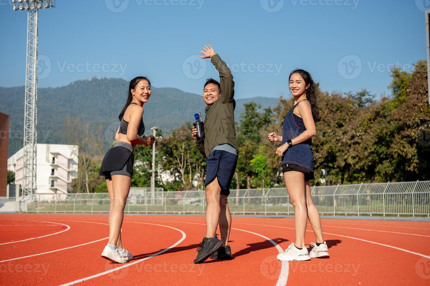 Portrait of a group of cheerful Asian athlete friends in sportswear running together in the stadium. photo