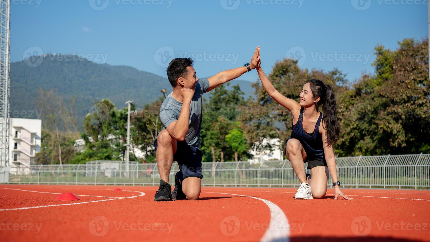 Two runners give high five while getting ready to run on a running track, training at a stadium photo