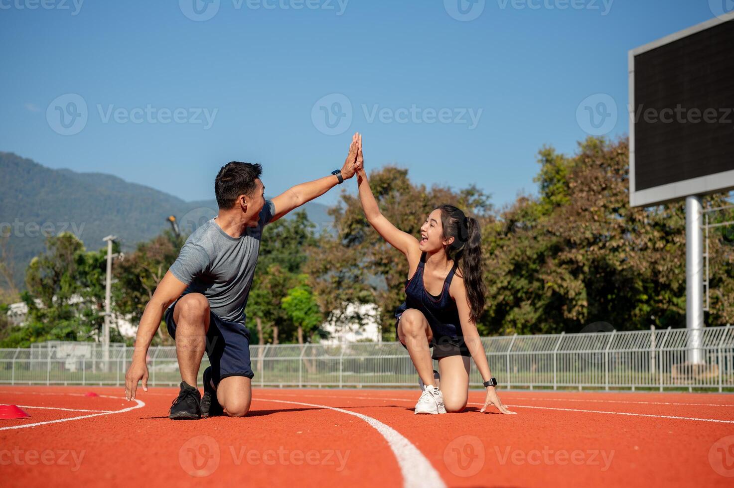 Two runners give high five while getting ready to run on a running track, training at a stadium photo