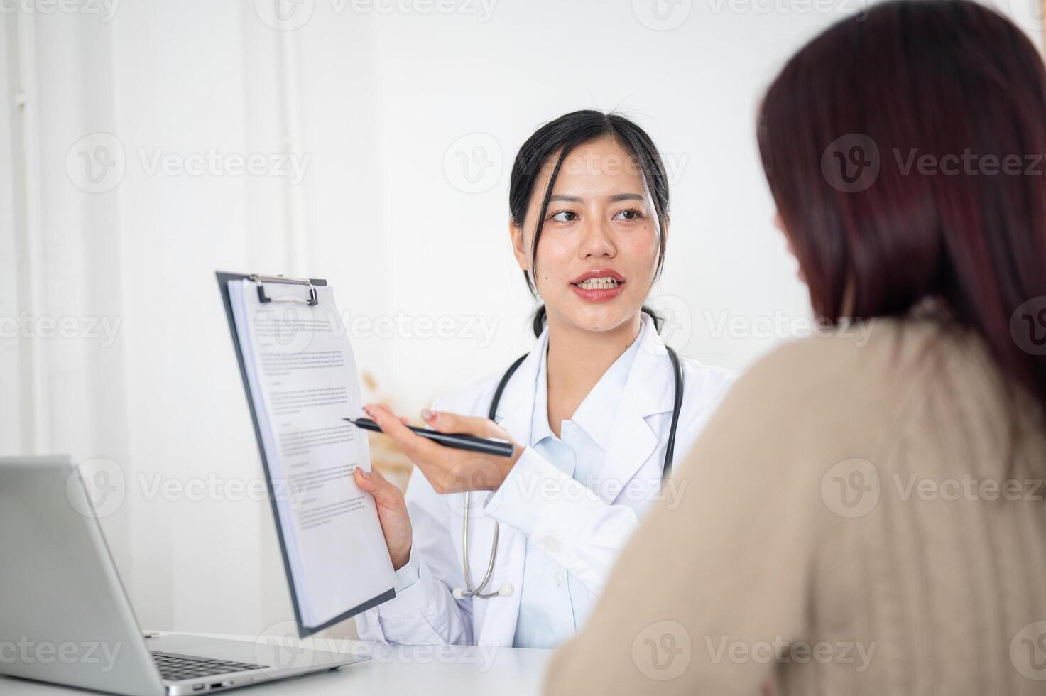 A doctor showing a medical paper to a patient while discussing the treatment plan at the hospital. photo