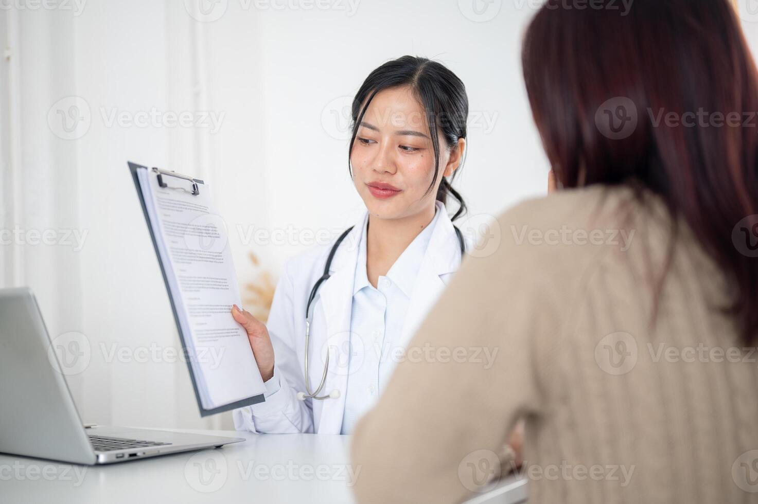 A doctor showing a medical paper to a patient while discussing the treatment plan at the hospital. photo