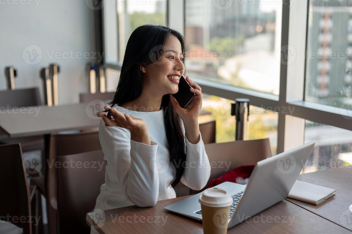A businesswoman talking on the phone with her client while working remotely from a coffee shop. photo