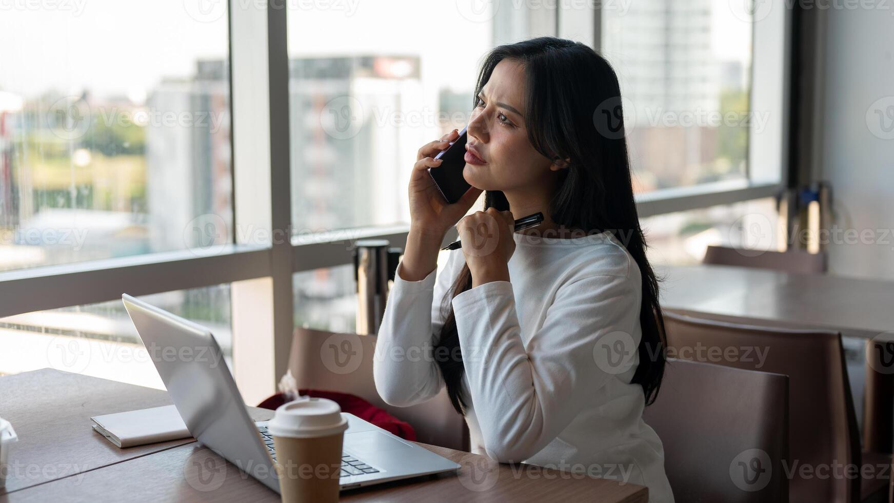 A businesswoman talking on the phone with her client while working remotely from a coffee shop. photo